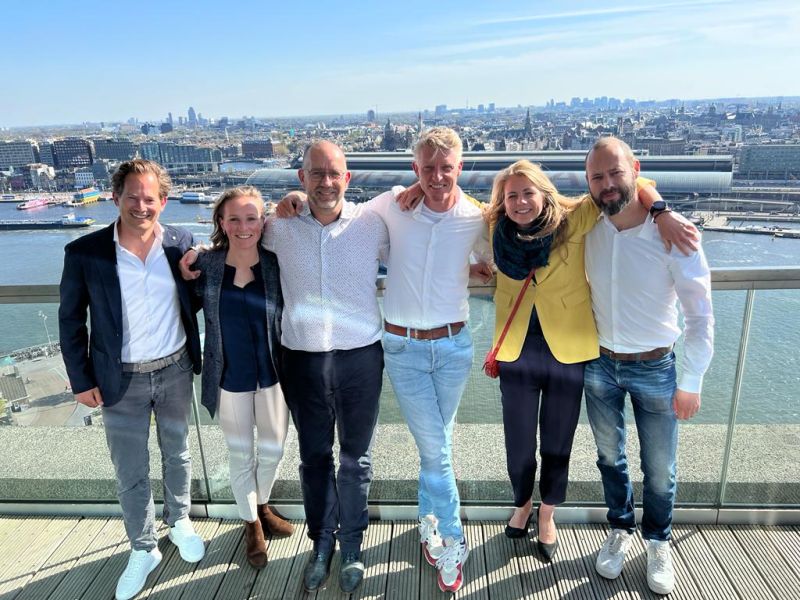 Photo of the team of Omnimap and investors celebrating the 3 mio eur investment with the skyline of amsterdam in the background
